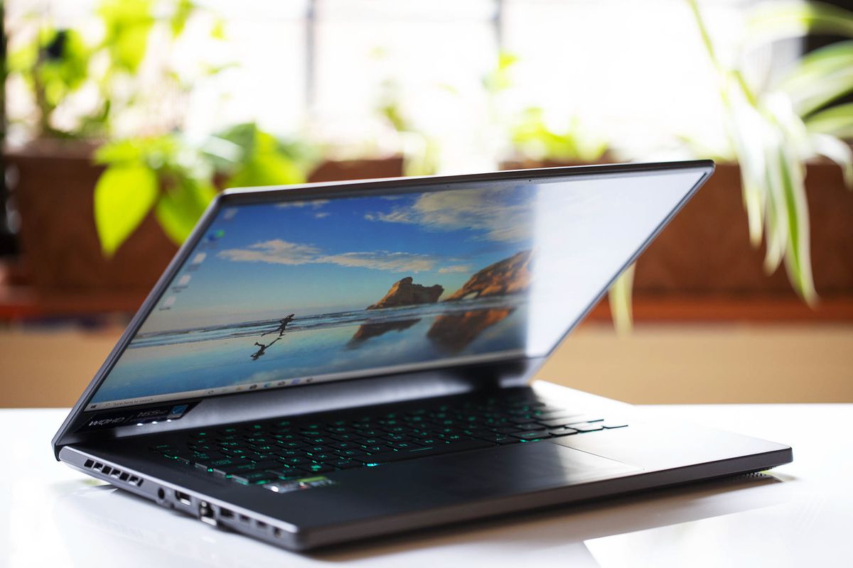 Asus ROG Zephyrus G15 pe jumătate deschis, ușor înclinat spre dreapta.  Ecranul afișează două stânci mari cu o persoană care aleargă spre ele, văzută peste un corp de apă.