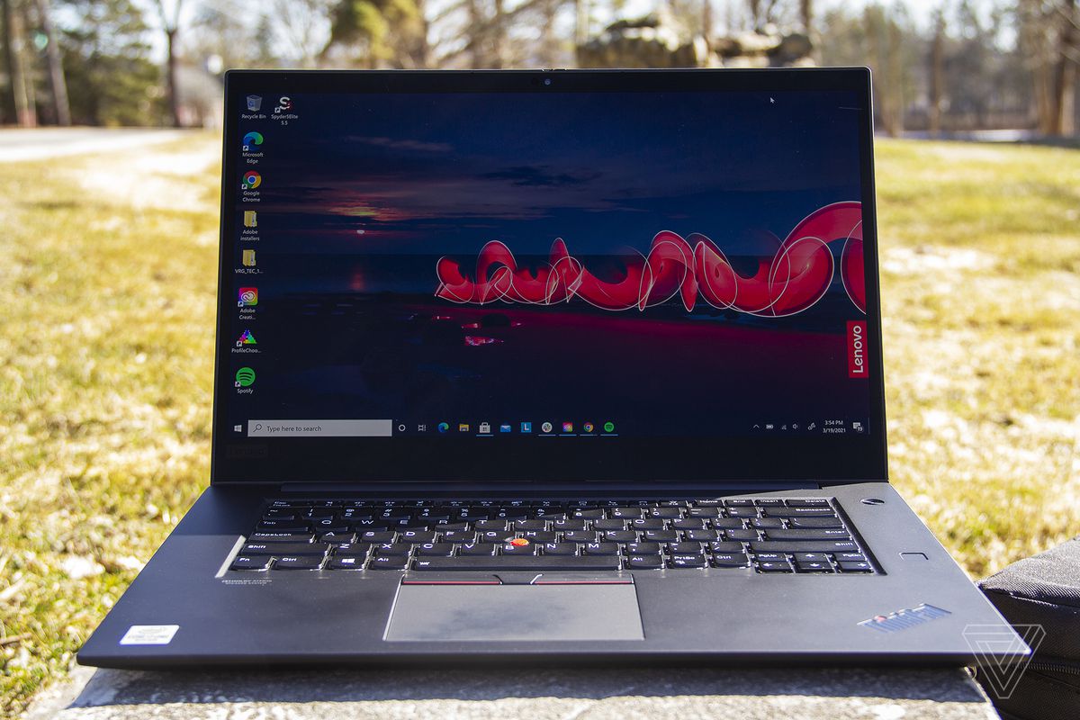Thinkpad X1 Extreme Gen 3 se deschide pe o placă de piatră în aer liber.  Ecranul afișează o scenă de noapte în aer liber, cu sigla Lenovo în partea dreaptă.