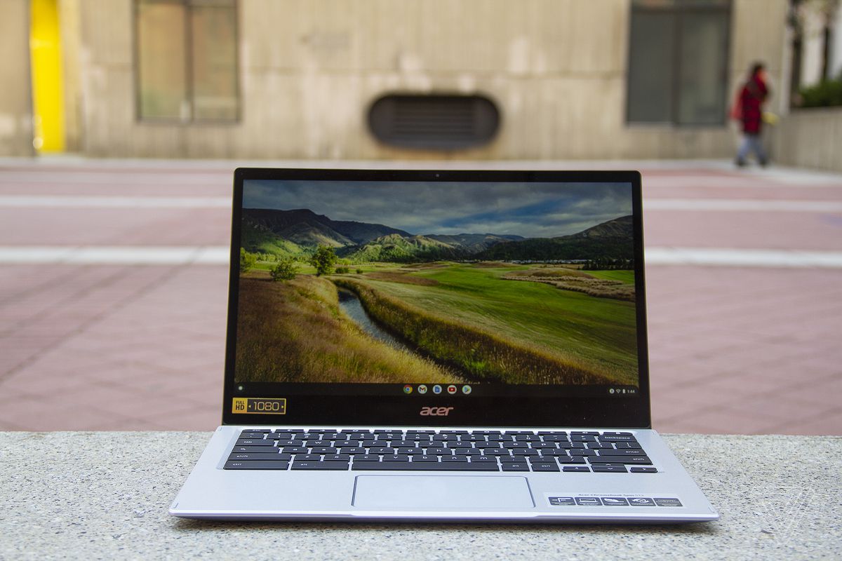 Chromebookul Acer Spin 513 este așezat pe o bancă de piatră, deschisă.  Ecranul afișează o scenă pastorală.