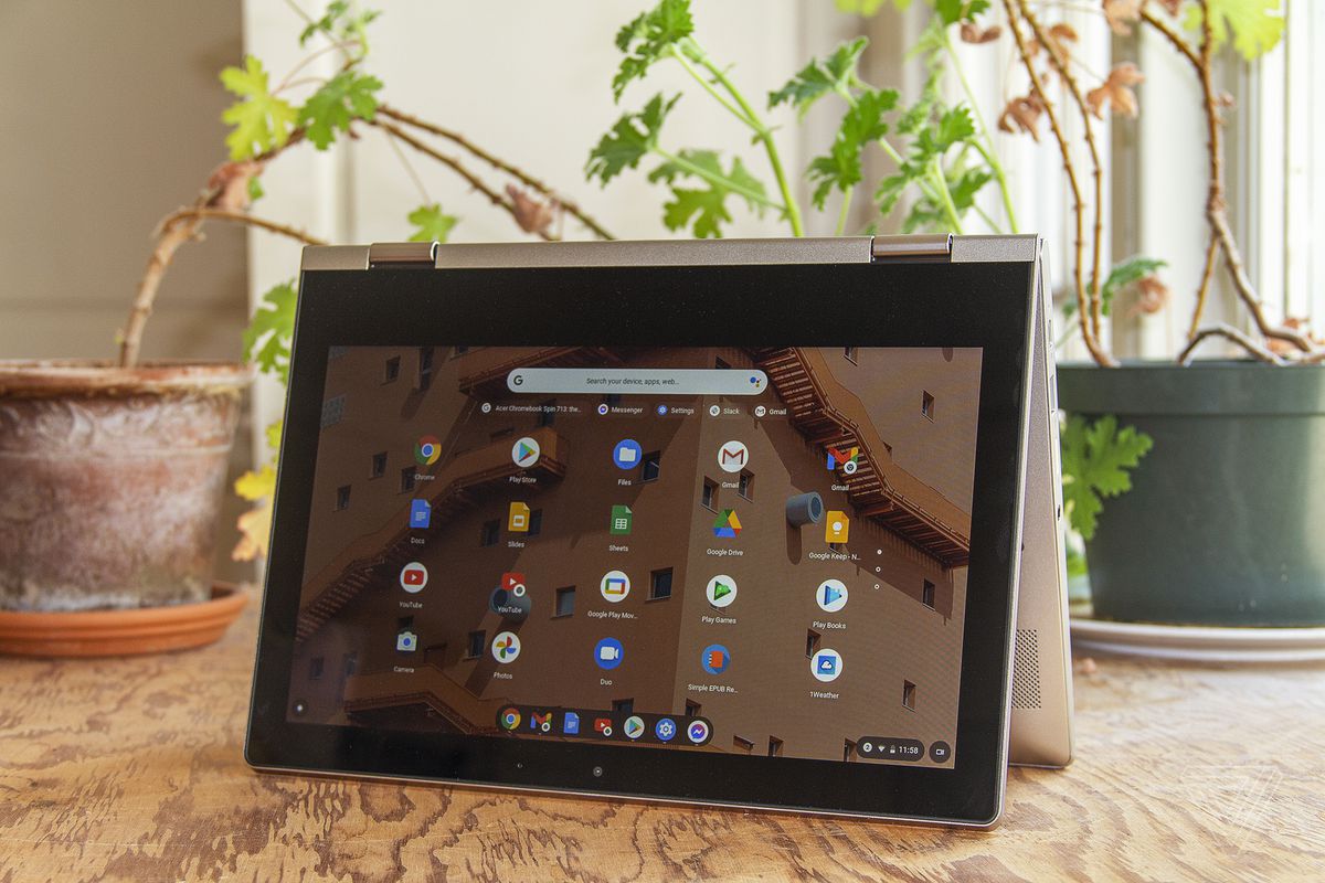 Chromebookul Lenovo Ideapad Flex 3 în modul cort, cu ecranul orientat spre cameră, înclinat ușor spre stânga, stă pe o masă cu două plante de apartament în fundal.  Ecranul afișează o grilă de pictograme ale aplicației Chrome OS.