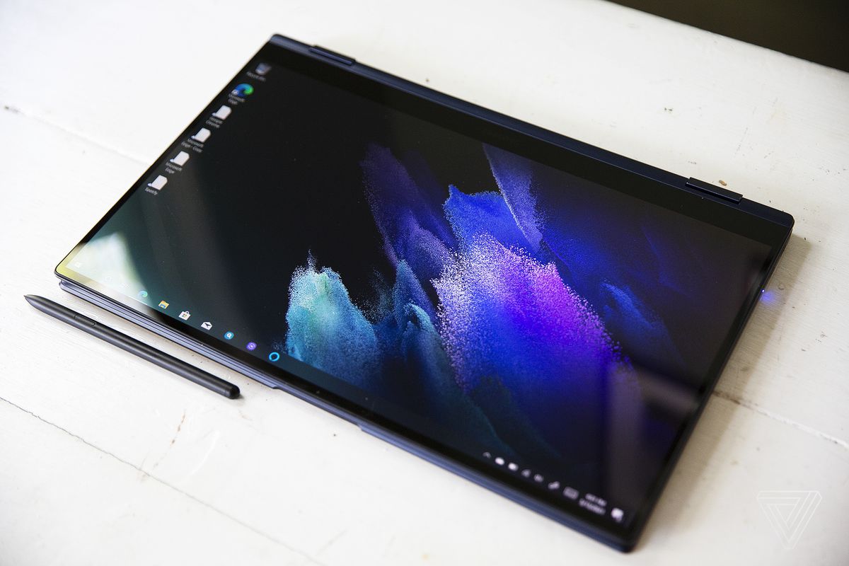 Samsung Galaxy Book Pro 360 (15 inci) în modul tabletă cu stylusul de sub el pe o masă albă. Ecranul afișează un model pastel purpuriu pe un fundal întunecat.