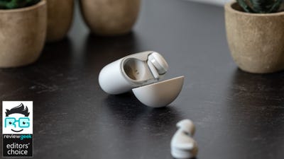 Pixel Buds O serie cu un mugur în carcasă și celălalt pe masă, carcasă deschisă