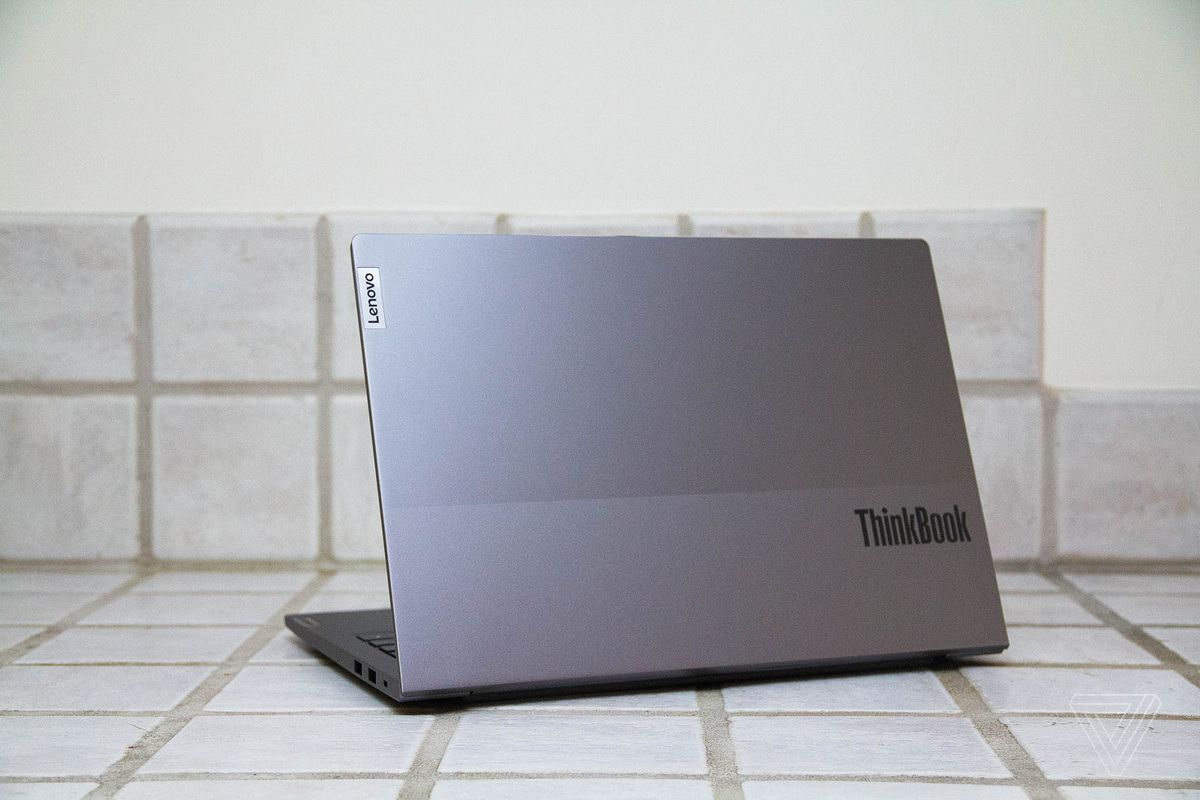 Lenovo ThinkBook 13s pe un blat din dale albe văzut din spate, înclinat spre stânga.