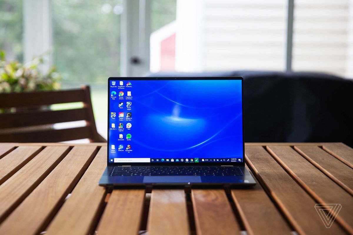 Dell Latitude 9420 se deschide pe o masă de verandă din lemn.  Ecranul afișează un fundal albastru pentru desktop.