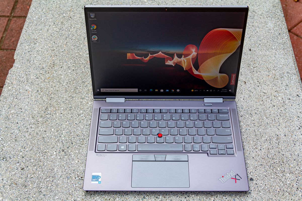 Lenovo ThinkPad X1 Yoga Gen 6 se deschide pe o bancă de piatră văzută de sus.  Ecranul afișează o scenă de noapte în aer liber, cu un banner portocaliu care traversează și bannerul Lenovo în partea dreaptă jos.