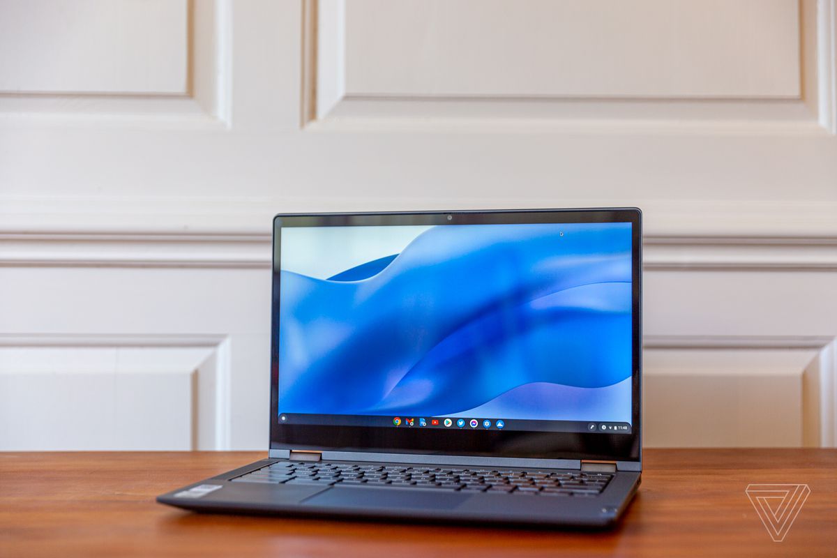 Chromebookul Lenovo Flex 5 este deschis, înclinat spre stânga.  Ecranul afișează un fundal ondulat albastru.