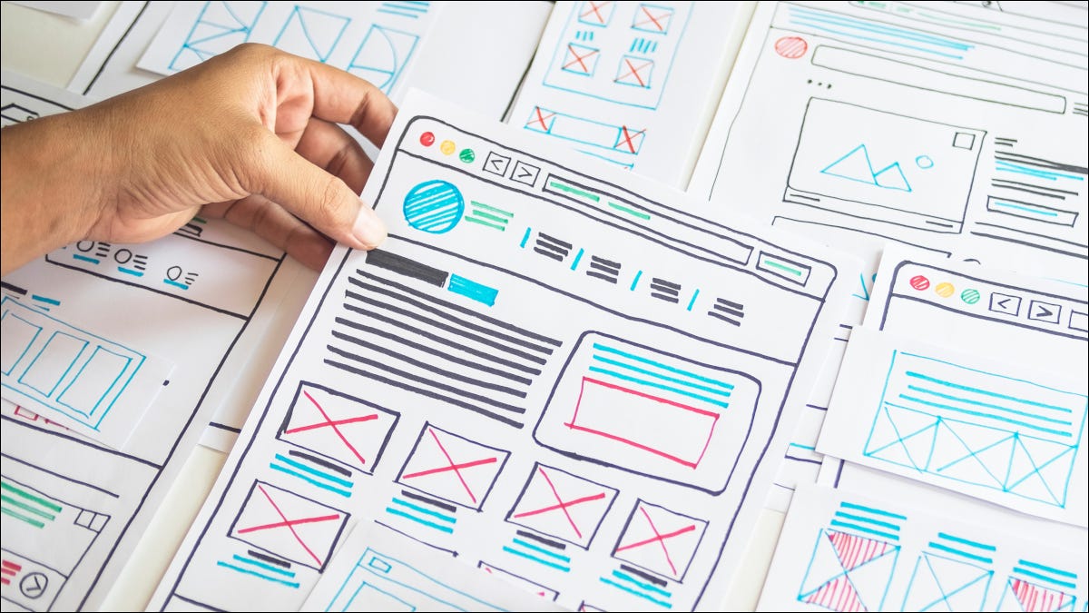 Mână ținând o hârtie cu desene colorate UX