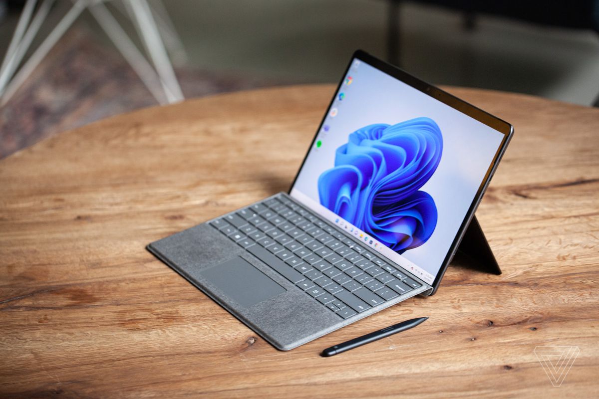 Surface Pro 8 văzut de sus și în dreapta pe o masă cu Surface Slim Pen 2 lângă acesta și tastatura cu semnătură atașată.  Ecranul afișează un vârtej albastru pe un fundal alb.
