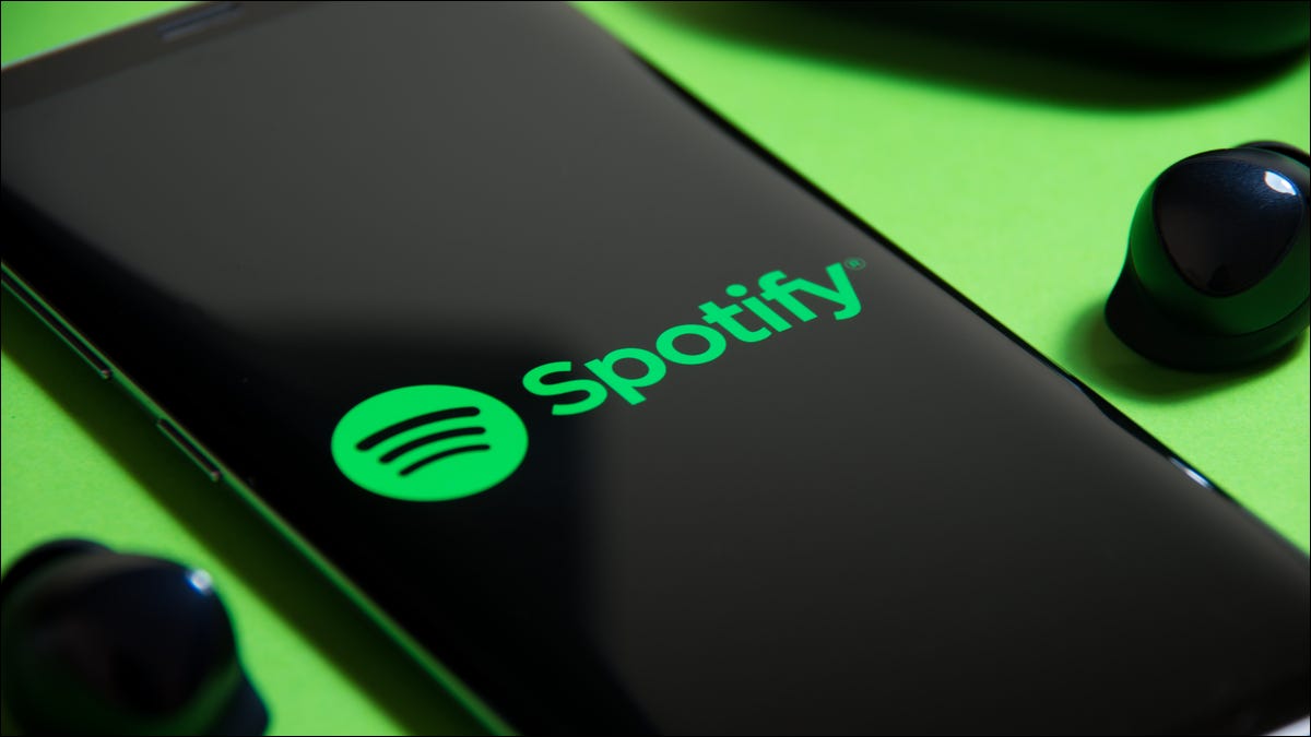 Sigla Spotify pe un smartphone lângă căști cu adevărat wireless